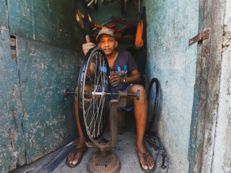 A skilled repairman fixing a bicycle wheel in his workshop, surrounded by tools and equipment.