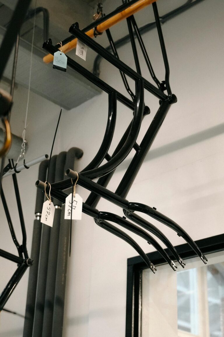 Hanging black steel bicycle frames in an Amsterdam workshop with natural lighting.